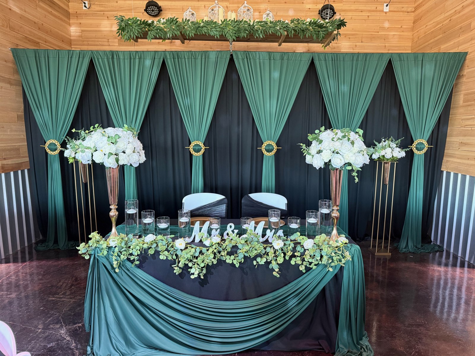 Emerald sweetheart table with white flowers and draped backdrop