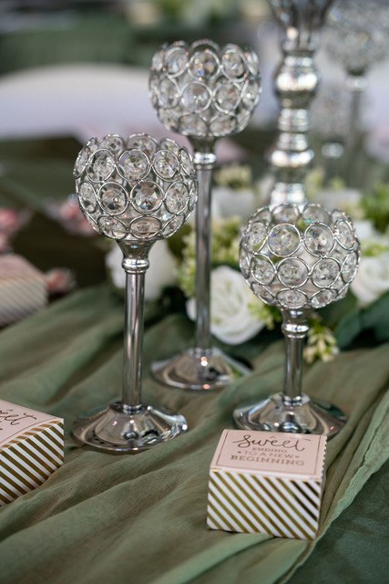 Crystal candleholders and greenery on a sage reception table
