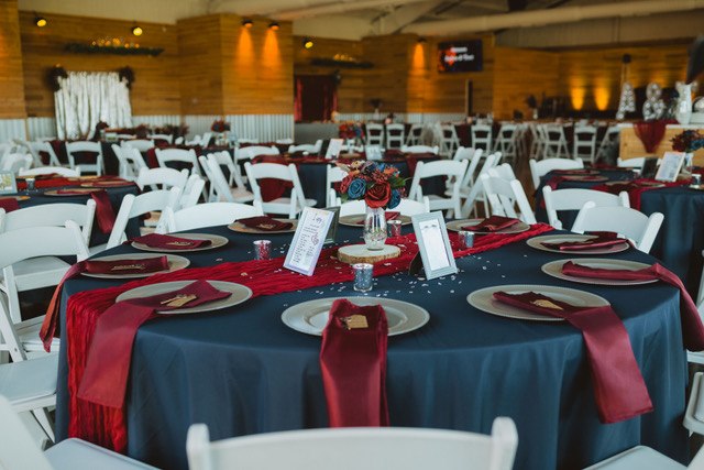 Round reception tables with red chair bands and table runners