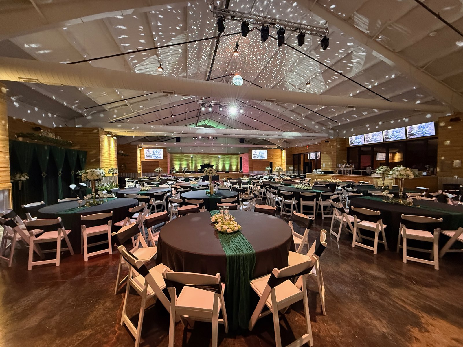 Round reception tables with emerald linens and warm overhead lighting