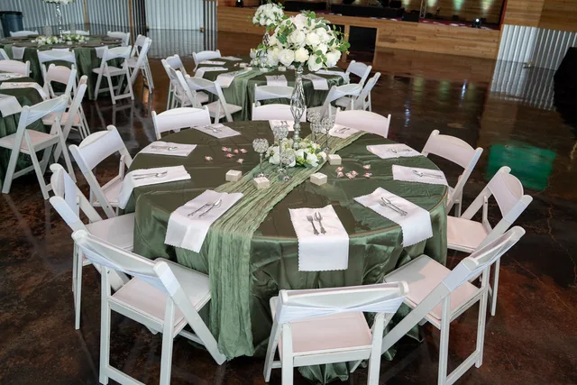 Sage linens and white chairs set for a wedding reception