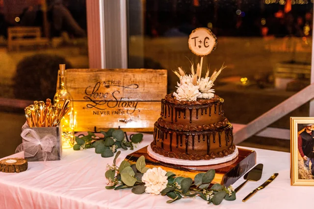 A tiered wedding cake and desserts on a warmly lit table