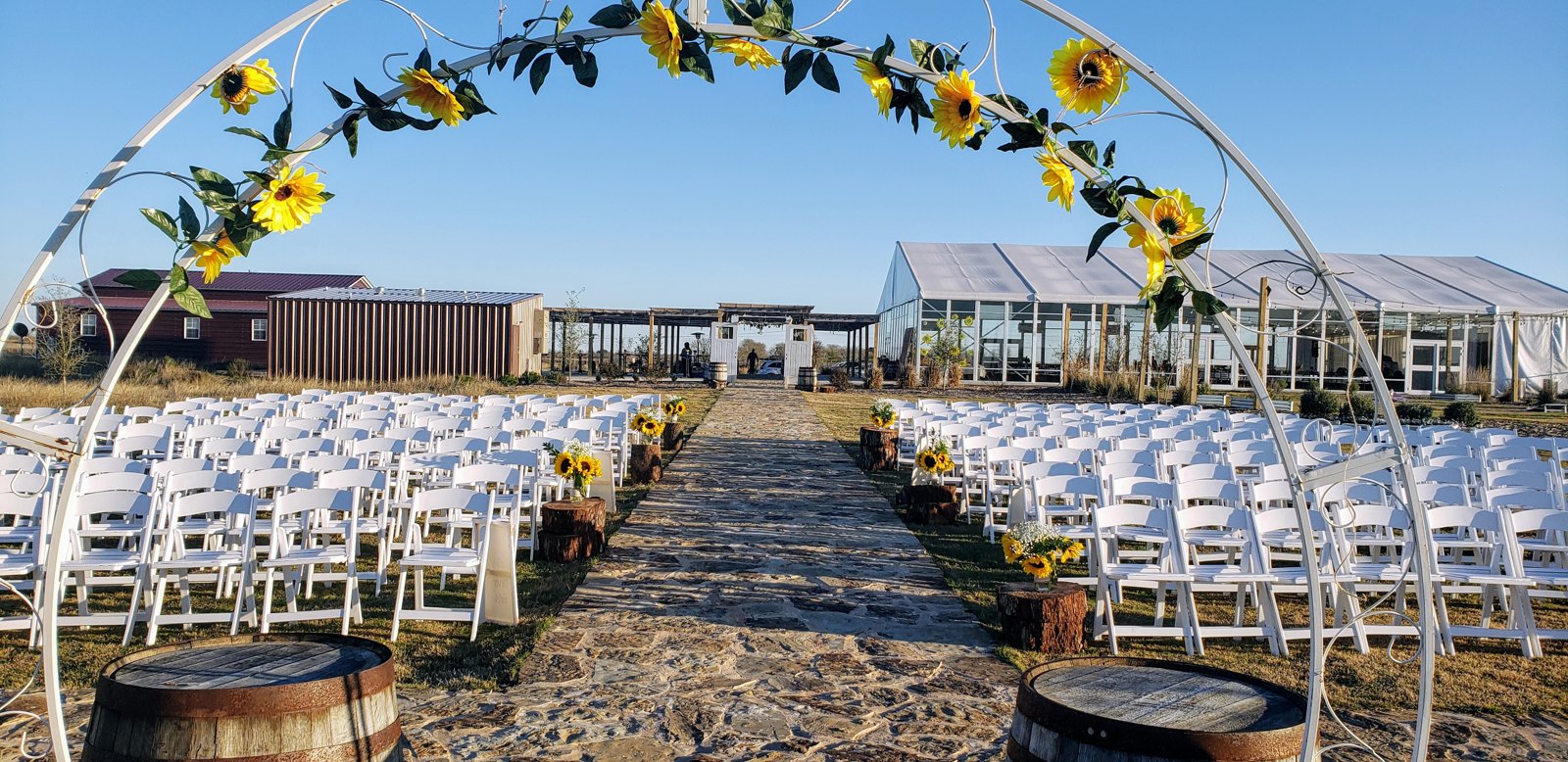 Sunflower floral arch with white ceremony chairs