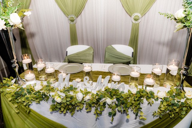 Sage and white sweetheart table with a floral backdrop