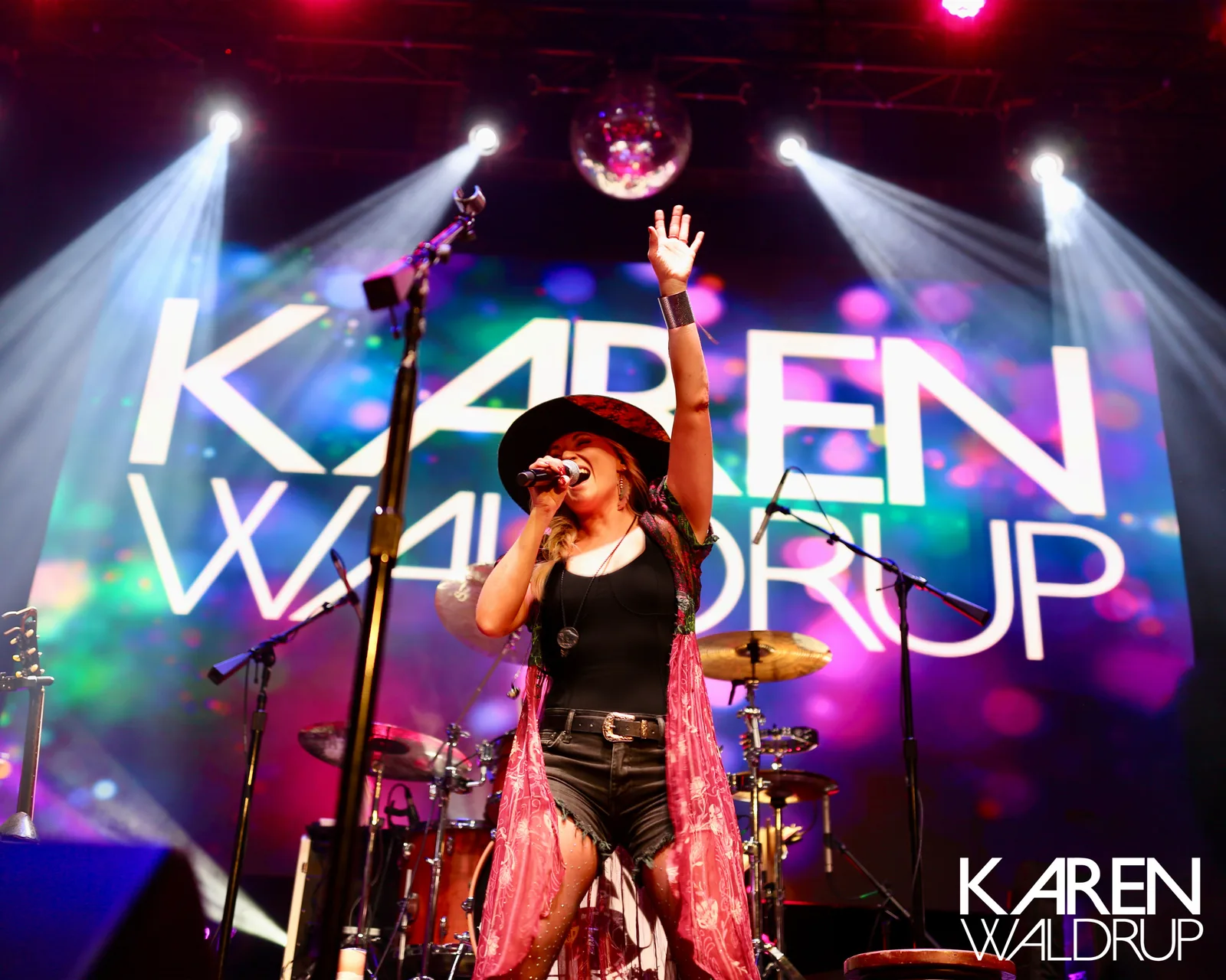 Karen Waldrup performing onstage under colorful concert lights