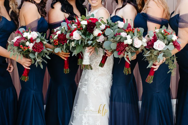 A wedding party holds red and white bouquets